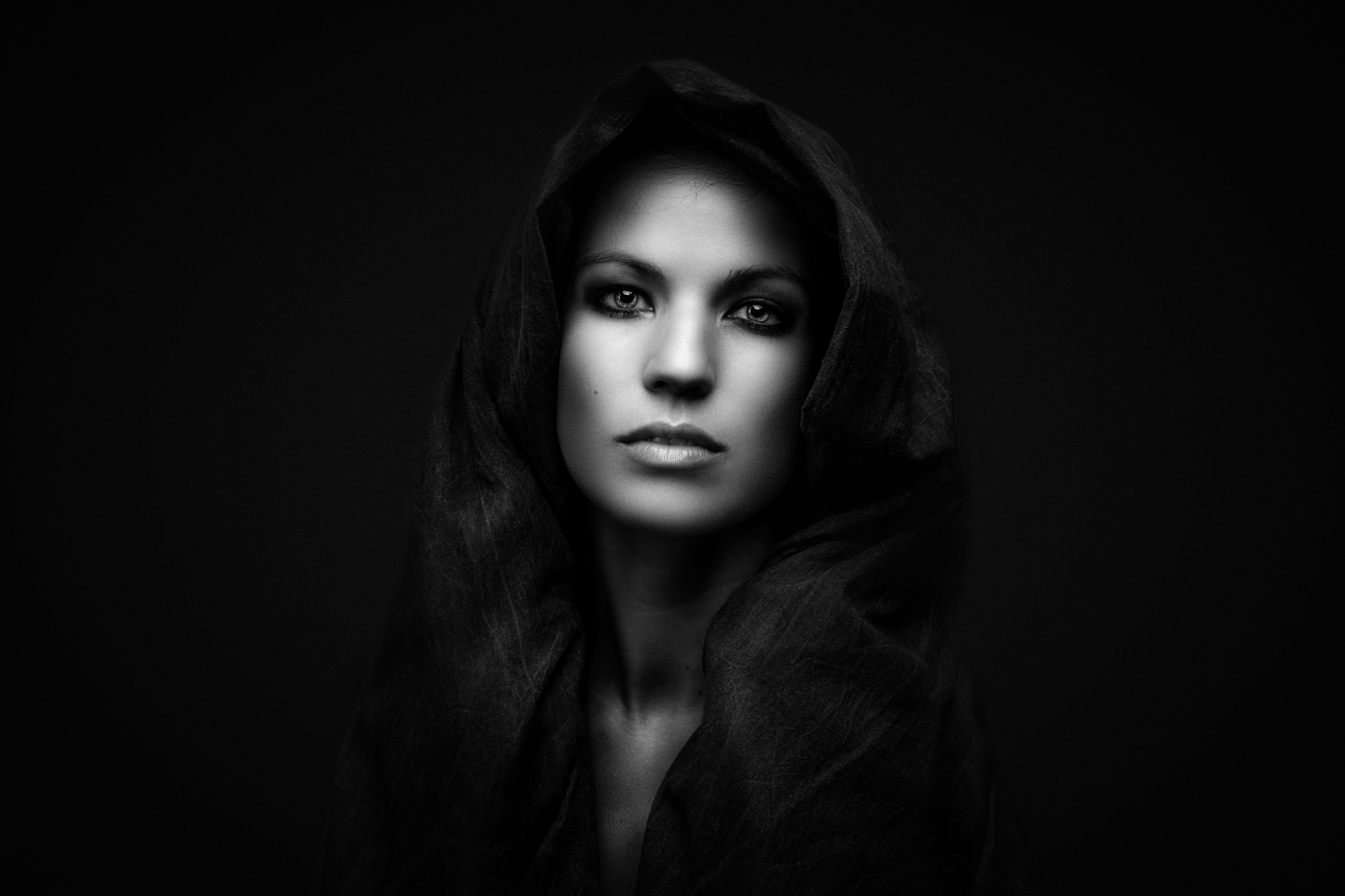 Striking black & white portrait of  of a woman with a cloak draped over her head.