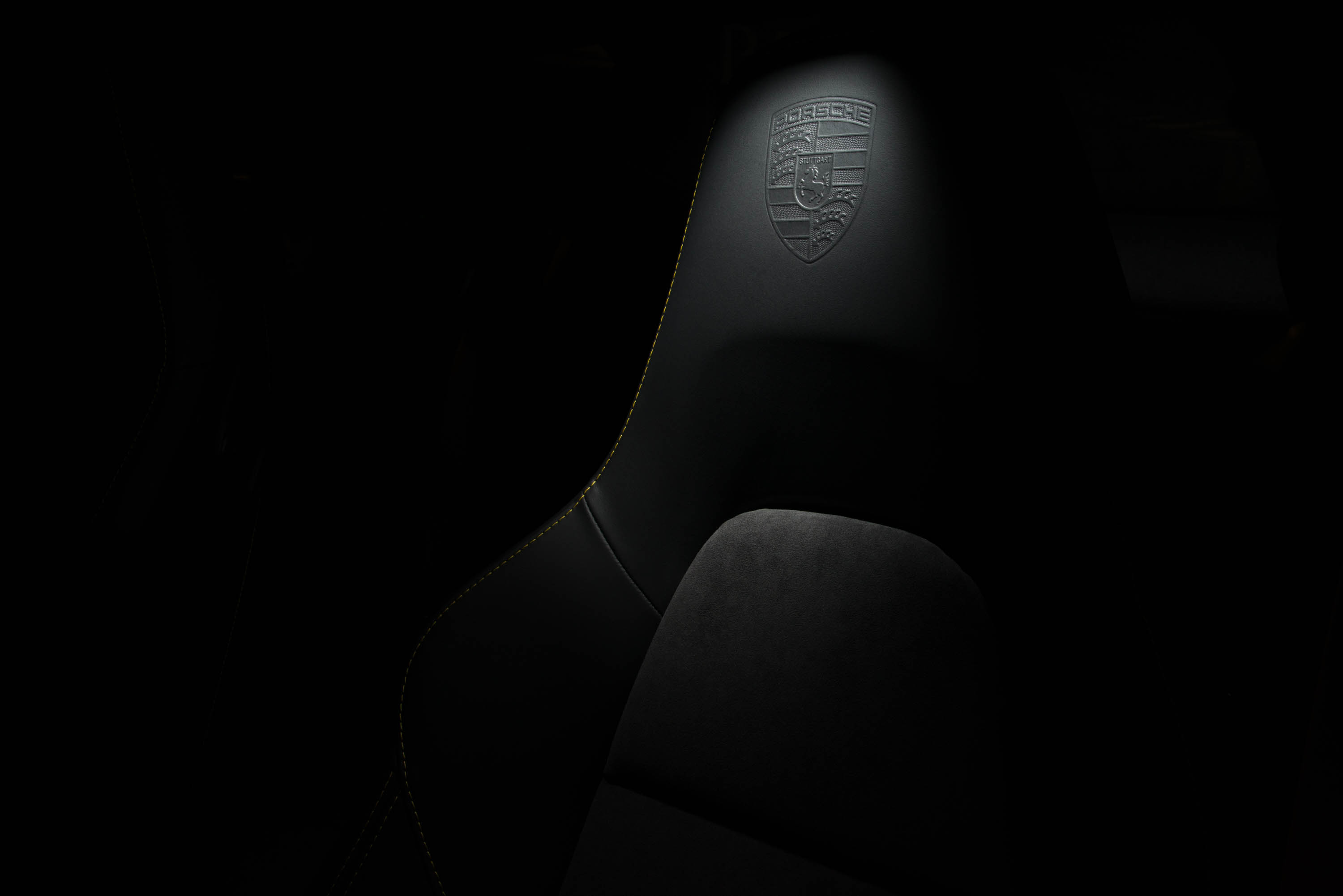 A commercial photograph of the front seat of a Porsche automobile, lit with low-key dramatic lighting.